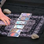 immagine che ritrae sei carte dei tarocchi disposte in fila orizzontale sopra un panno nero con decorazioni bianche