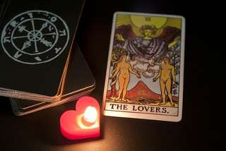immagine che ritrae la carta degli Innamorati ed una candela rossa accesa a forma di cuore