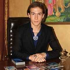 immagine di un cartomante uomo seduto ad un tavolo di legno in cui sono disposte diverse carte 